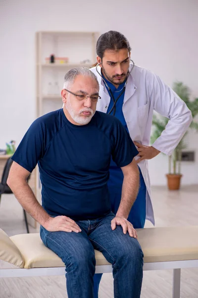 Yaşlı erkek hasta genç erkek doktoru ziyaret ediyor. — Stok fotoğraf