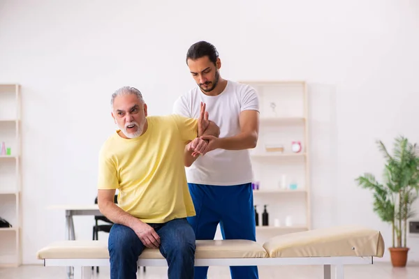 Yaşlı erkek hasta, genç erkek doktor masörünü ziyaret ediyor. — Stok fotoğraf