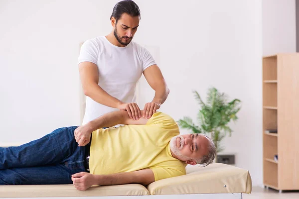 Oude mannelijke patiënt op bezoek bij jonge mannelijke arts chiropractor — Stockfoto