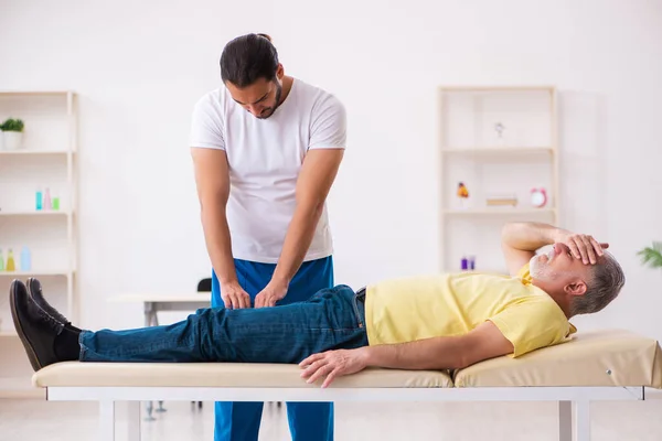 Old male patient visiting young male doctor chiropractor — Stock Photo, Image