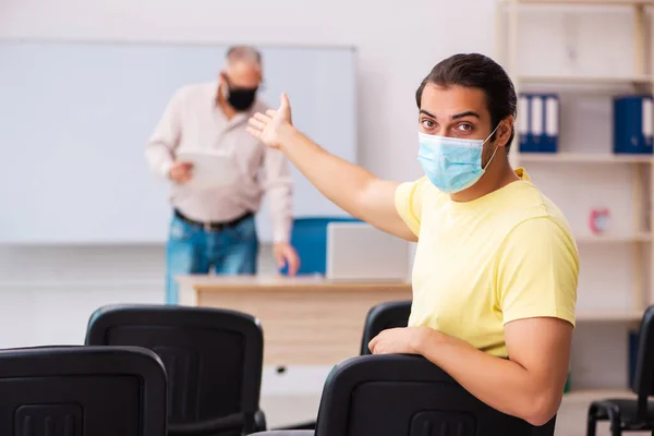 Ung manlig student och erfaren lärare i pandemi koncept — Stockfoto