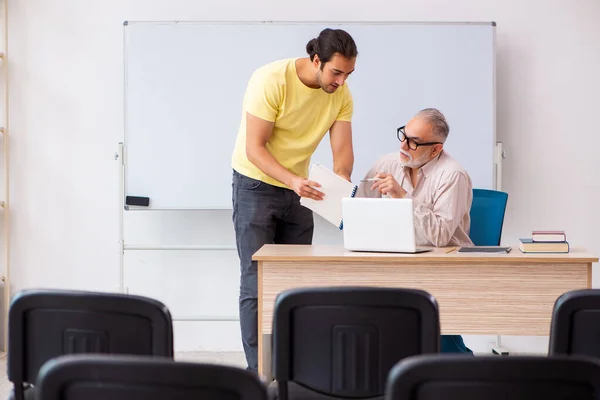 Jonge mannelijke student en ervaren leraar pandemisch concept — Stockfoto