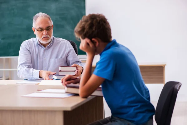 Oude mannelijke leraar en schooljongen in de klas — Stockfoto