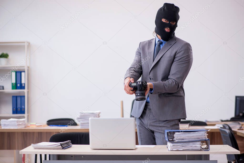 Young male employee in industrial espionage concept