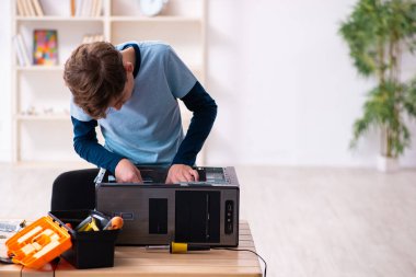 Çocuk atölyede bilgisayar tamir ediyor.