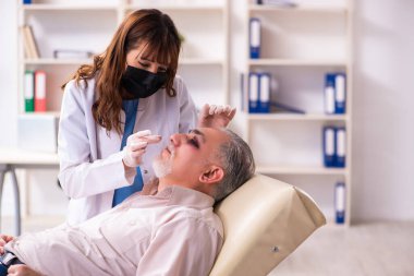 Yaşlı adam estetik ameliyat için genç bayan doktoru ziyaret ediyor.