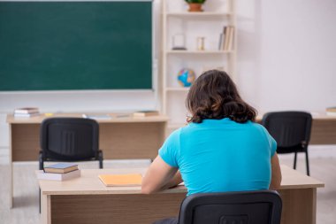 Yeşil panonun önünde genç bir erkek öğrenci.