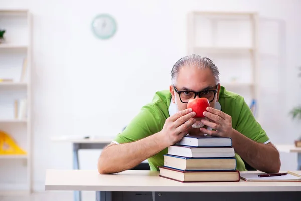 Oude mannelijke student eet appel tijdens de voorbereiding van het examen — Stockfoto