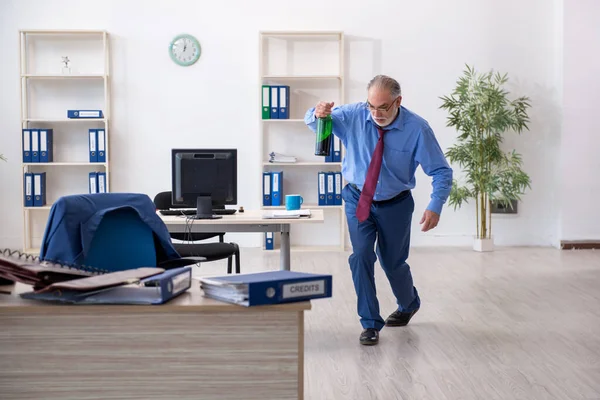 Oude mannelijke werknemer drinkt alcohol op kantoor — Stockfoto