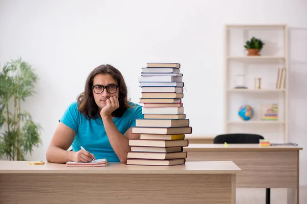 Giovane studente maschio e un sacco di libri in classe — Foto Stock