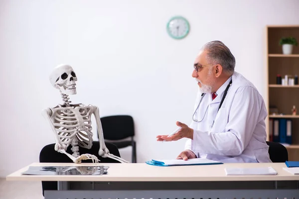 Klinikteki yaşlı erkek doktor ve iskelet hastası. — Stok fotoğraf