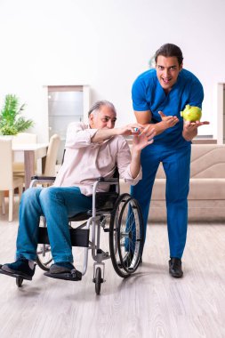 Tekerlekli sandalyedeki yaşlı adam ve genç kötü bakıcı.