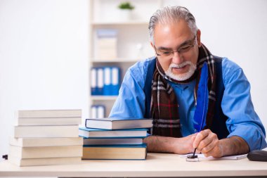 Yaşlı erkek yazar tüyle kitap yazıyor.