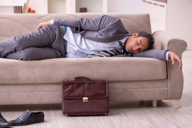 Yorgun genç işadamı işten sonra eve geliyor.