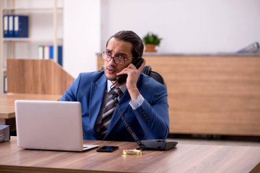 Genç erkek çalışan işyerinde oturuyor.