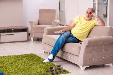 Yaşlı adam evde spor egzersizleri yapıyor.