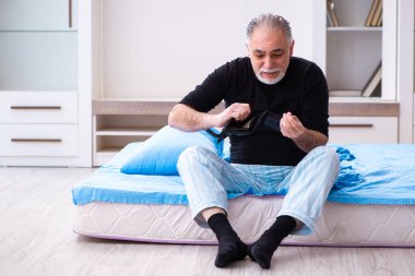 Yaşlı adamın yatak odasında parası bitiyor.