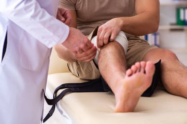Deneyimli doktor travmatolog genç erkek hastayı muayene ediyor.