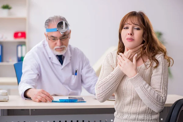 Giovane donna in visita vecchio medico maschio otorinolaringoiatra — Foto Stock