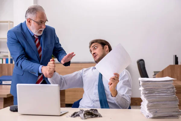 Young male employee and old boss burning papers at workplace — Stock Photo, Image