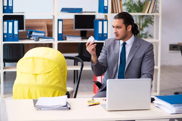 Joven empleado masculino que cuida del recién nacido en el lugar de trabajo — Foto de Stock