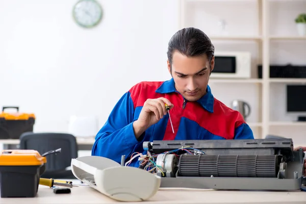 Jovem reparador reparando ar-condicionado no centro de garantia — Fotografia de Stock