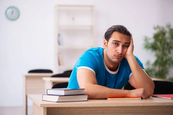 Erschöpfte männliche Schüler bereiten sich im Klassenzimmer auf die Prüfungen vor — Stockfoto