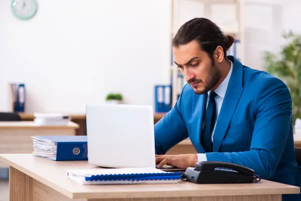 Joven empleado masculino y demasiados trabajan en la oficina — Foto de Stock