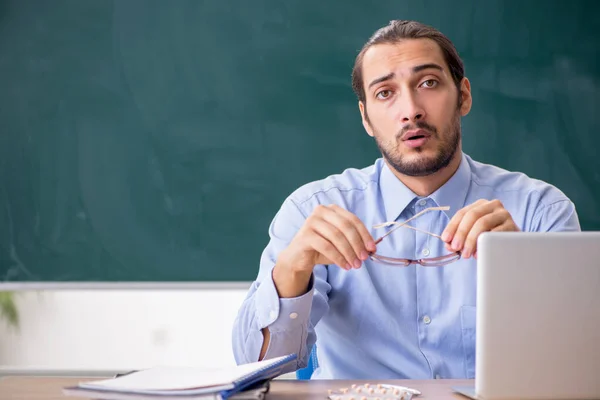 Jonge zieke mannelijke leraar in de klas — Stockfoto