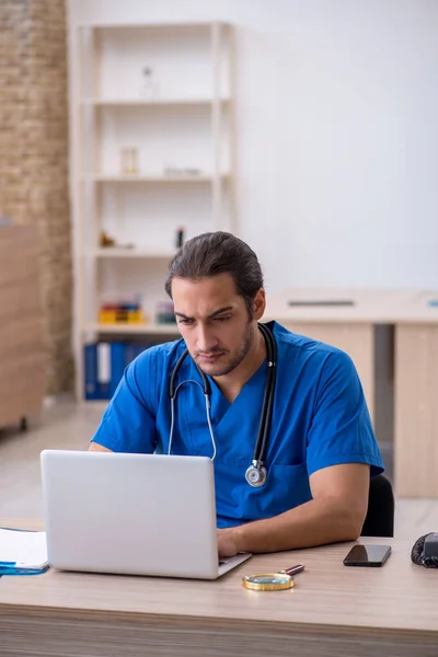 Ung manlig läkare som arbetar på kliniken — Stockfoto