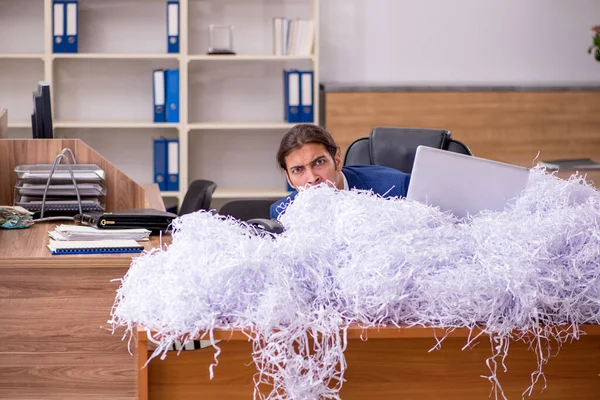 Joven empleado masculino y muchos papeles cortados en la oficina — Foto de Stock