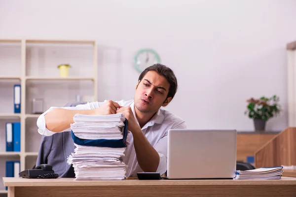 Jonge mannelijke werknemer ongelukkig met overmatig werk in het kantoor — Stockfoto