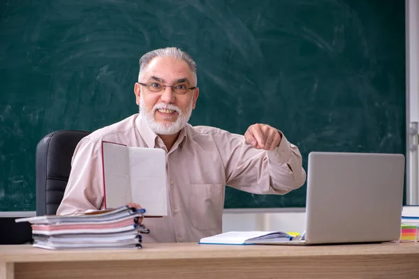 Oude mannelijke leraar zit in de klas — Stockfoto