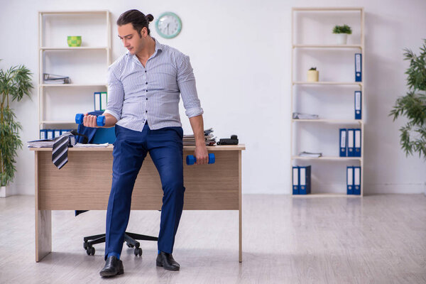 Молодой красивый работник делает упражнения в офисе