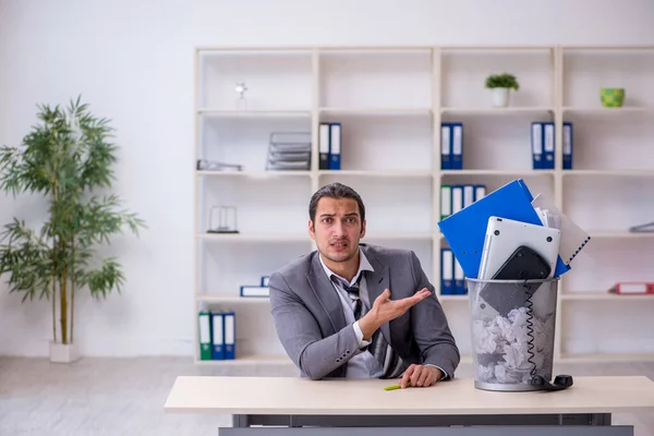 Fired young businessman with recycle bin in the office