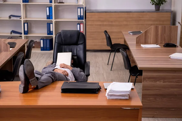 Молодой работник мужчина спит на рабочем месте — стоковое фото