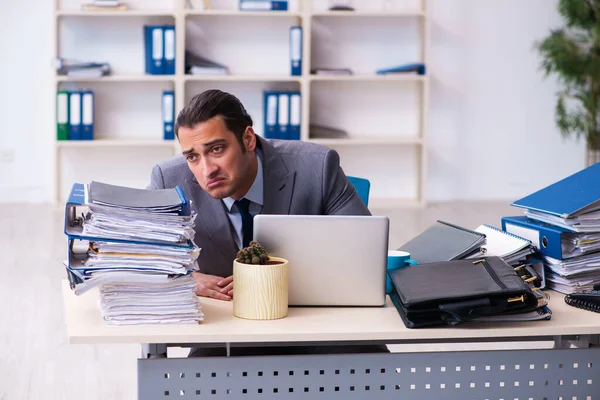 Joven empleado masculino infeliz con el trabajo excesivo — Foto de Stock