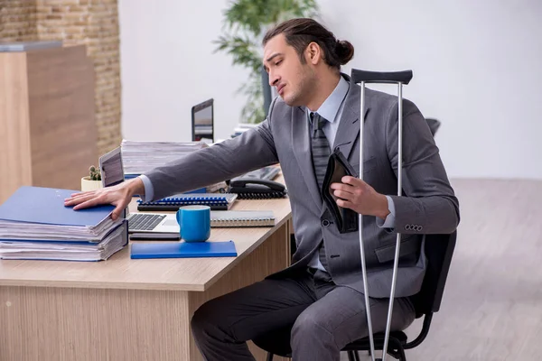 Young leg injured male employee working in the office — Stock Photo, Image