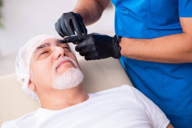 Yaşlı adam estetik ameliyat için erkek doktoru ziyaret ediyor.