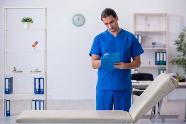 Genç erkek doktor hastanede not alıyor.