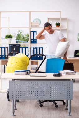 İş yerinde yeni doğan bebeğe bakan genç bir erkek işçi.