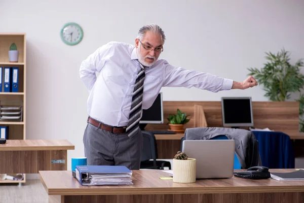 Vecchio dipendente maschio affetto da radicolite sul posto di lavoro — Foto Stock