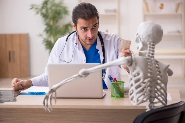 Jeune homme médecin et patient squelette à la clinique — Photo