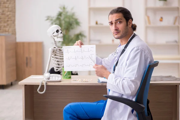 Młody lekarz kardiolog i pacjent ze szkieletem w klini — Zdjęcie stockowe