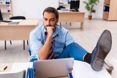 Ofisteki aşırı işten memnun olmayan genç bir erkek işçi.