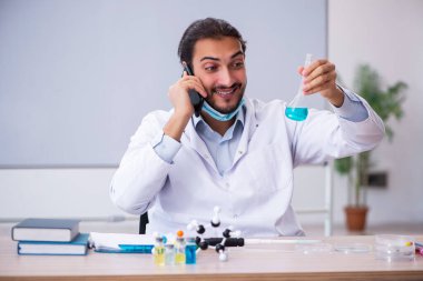 Sınıfta oturan genç erkek kimya öğretmeni.