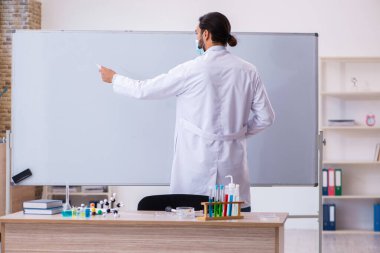 Sınıfta oturan genç erkek kimya öğretmeni.