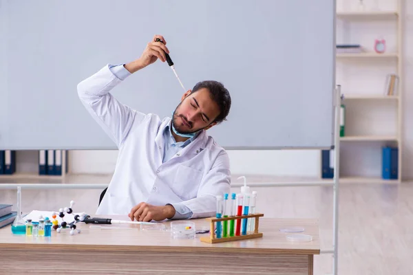 Mladý muž chemik učitel sedí ve třídě — Stock fotografie