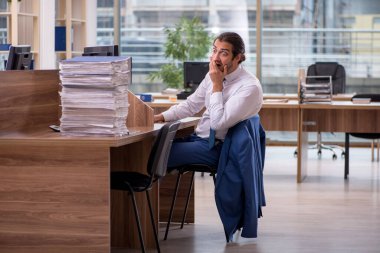 Ofisteki aşırı işten memnun olmayan genç bir erkek işçi.