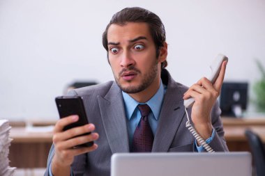 Ofisteki aşırı işten memnun olmayan genç bir erkek işçi.